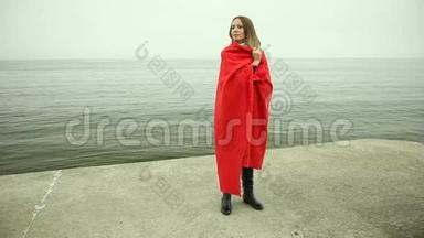 孤独悲伤的女孩，穿着红毯在海边